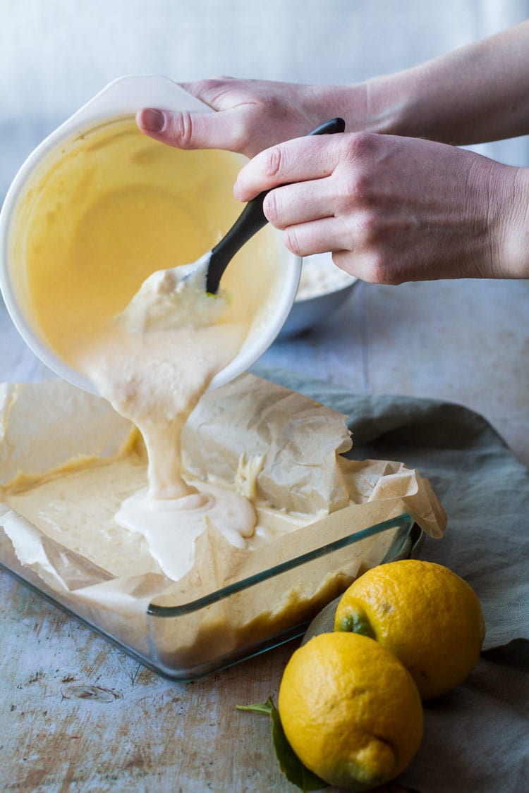 Pouring cake batter into prepared baking pan. Lemons in the corner. 