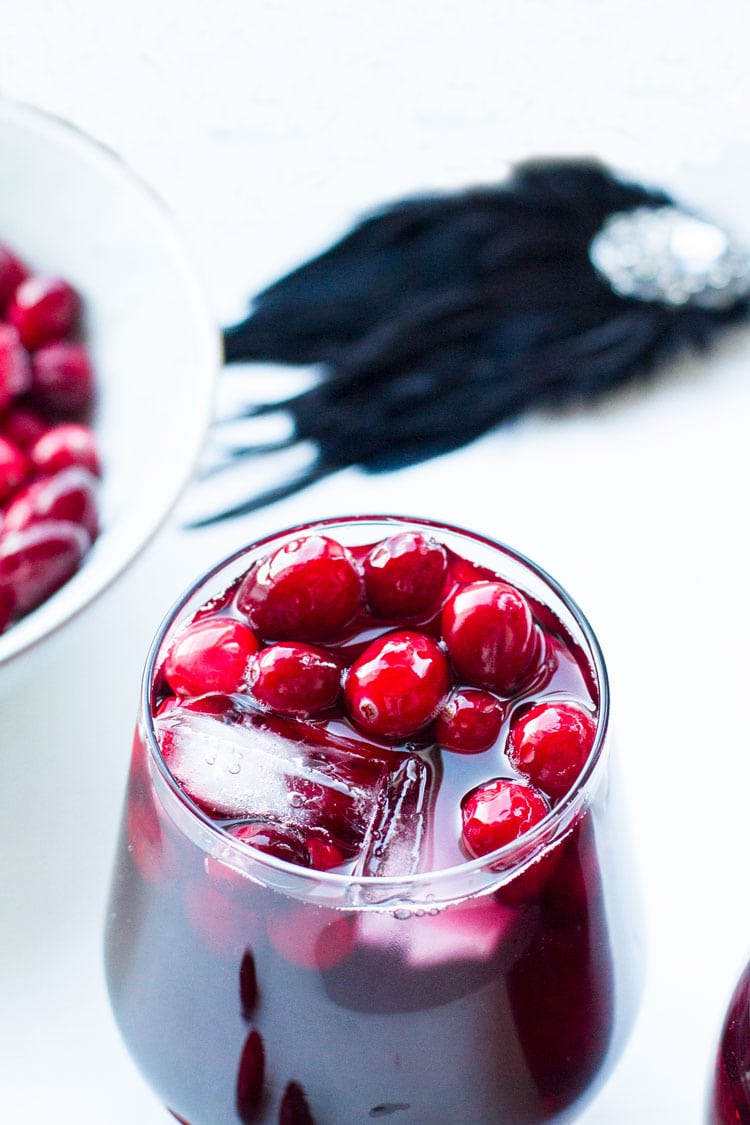 Stem-less wine glass with sangria, cranberries and ice cubes.