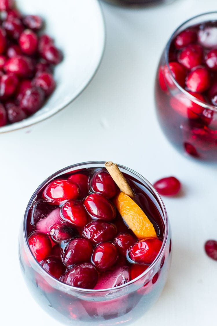 Cranberry sangria in a glass with fresh cranberries and orange wedge.