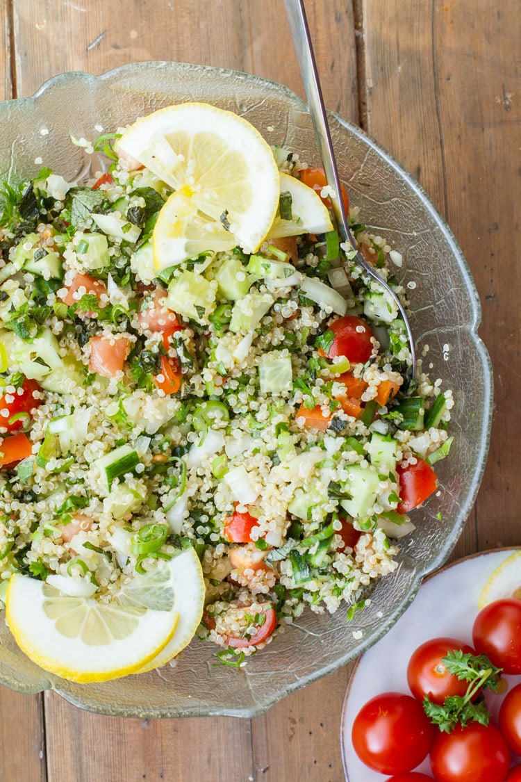Tabbouleh with quinoa and lemon slices in a large glass bowl. Flatlay.