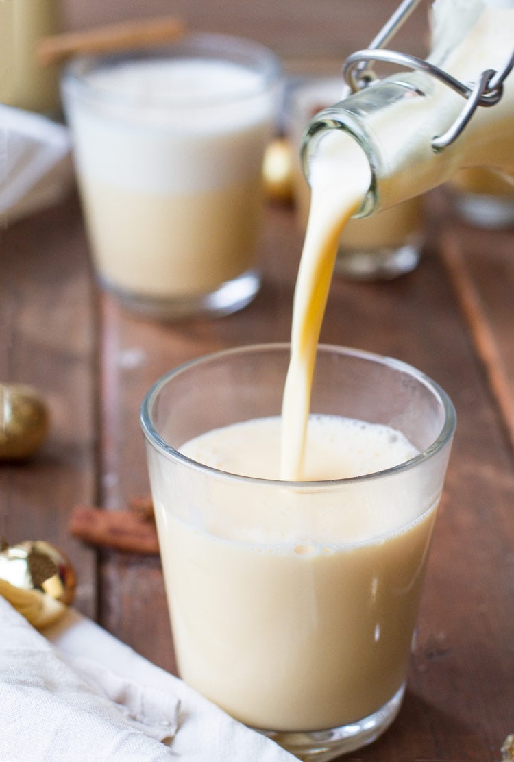 Pouring homemade eggnog in a small glass.