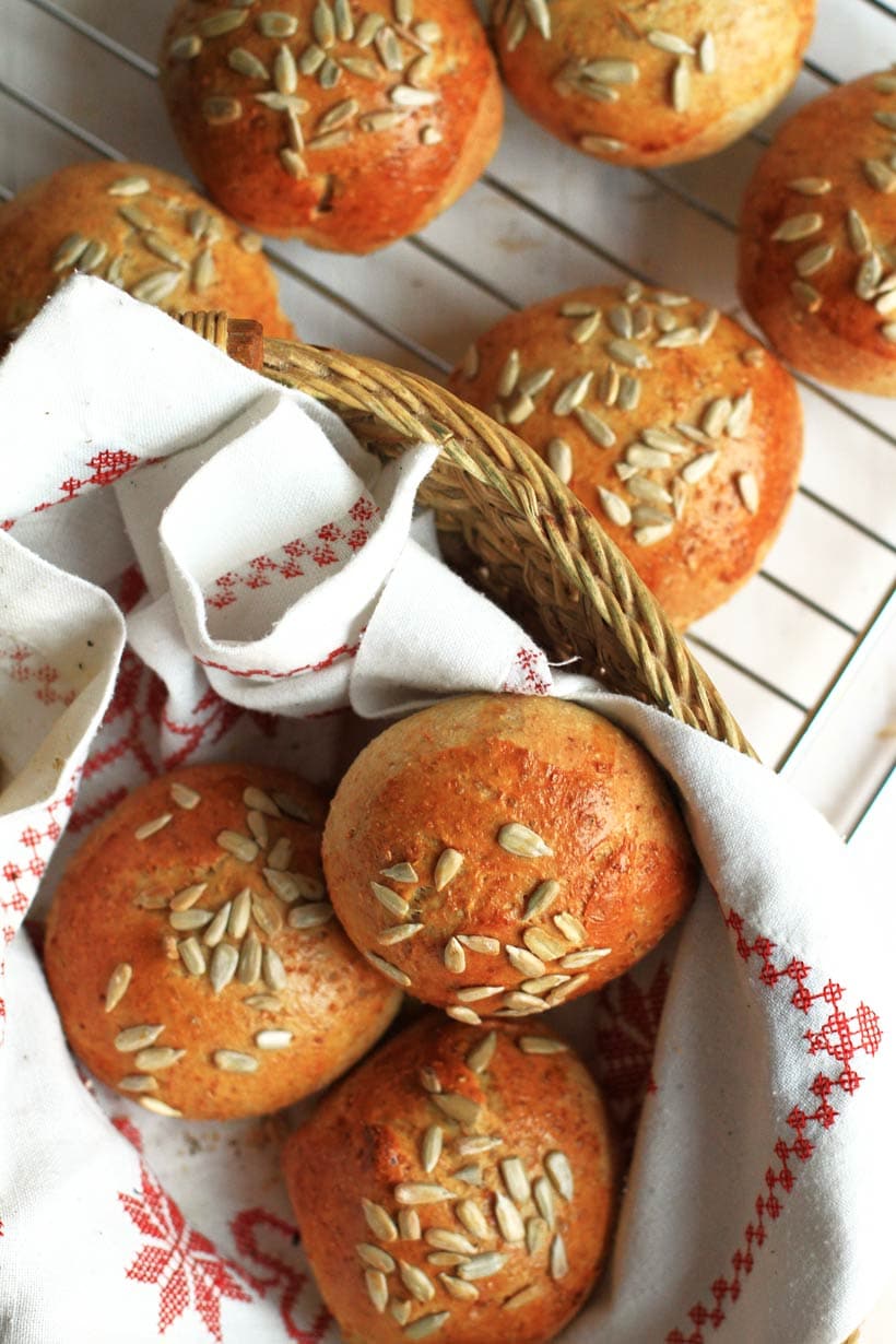 Whole Wheat Bread Rolls in a bread basket and some one a cooling rack.