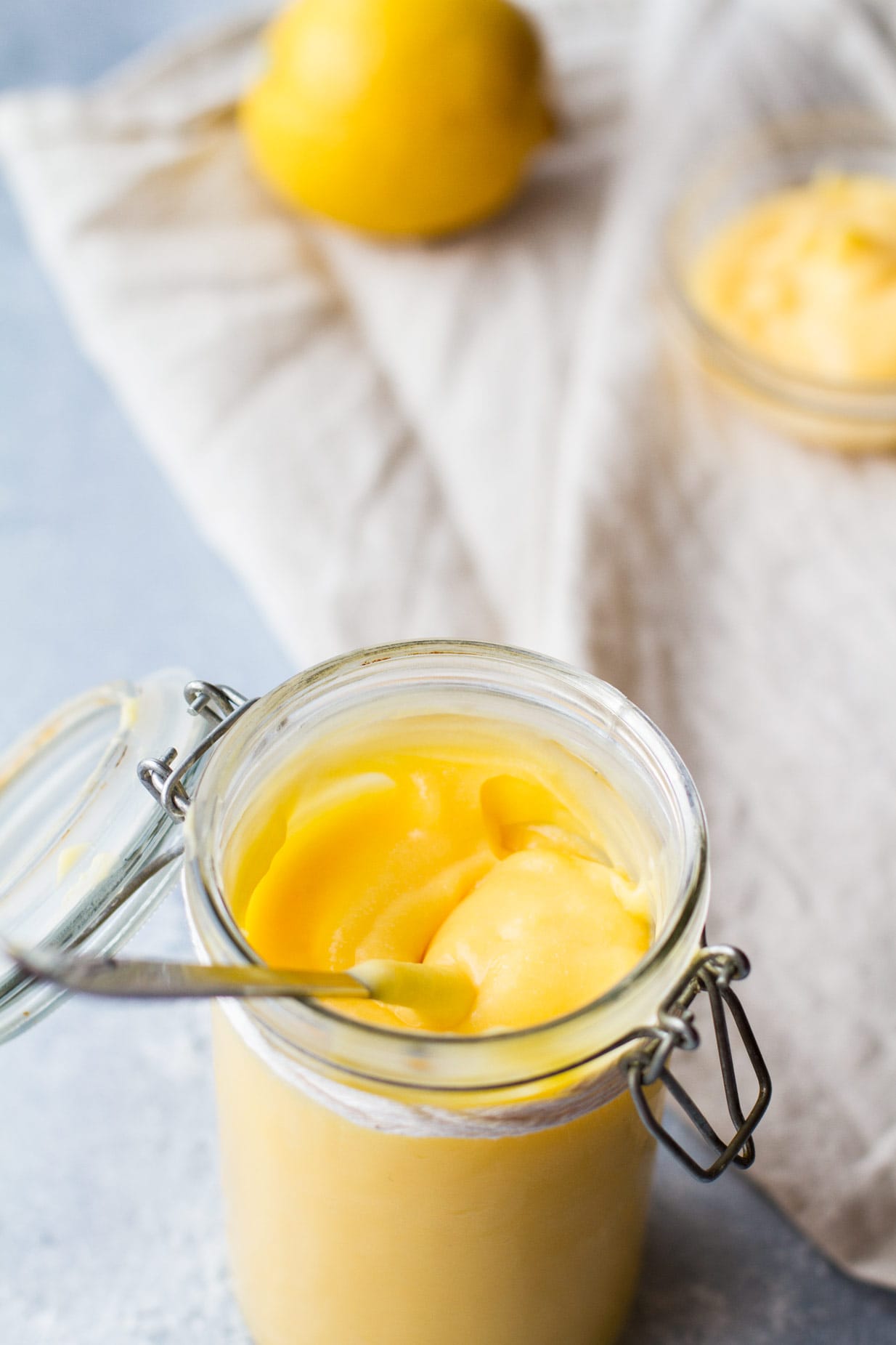 Glass jar with homemade lemon curd and a spoon. 