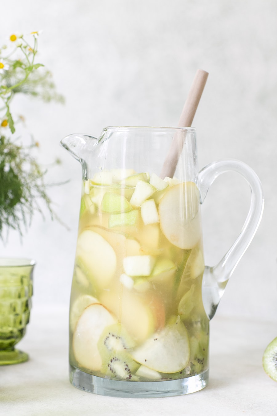 Whiskey Sangria in a clear pitcher, kiwis, apples, pears and grapes. 