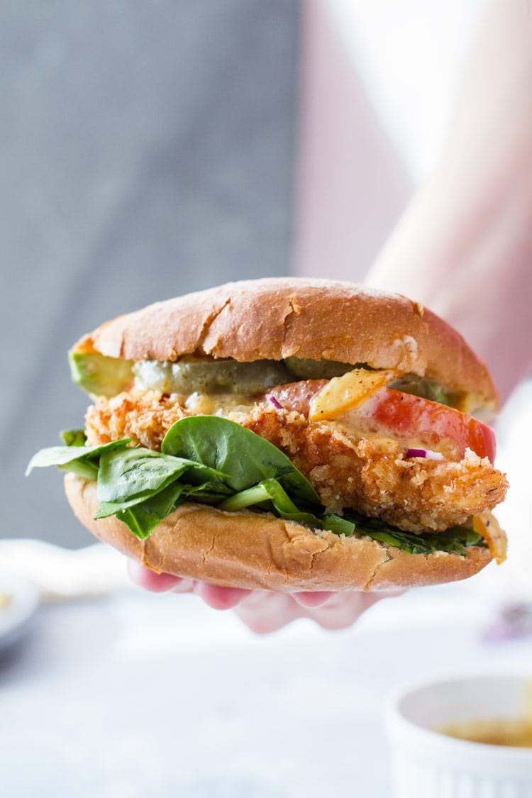 A panko chicken burger with lettuce, tomatoes and pickles.