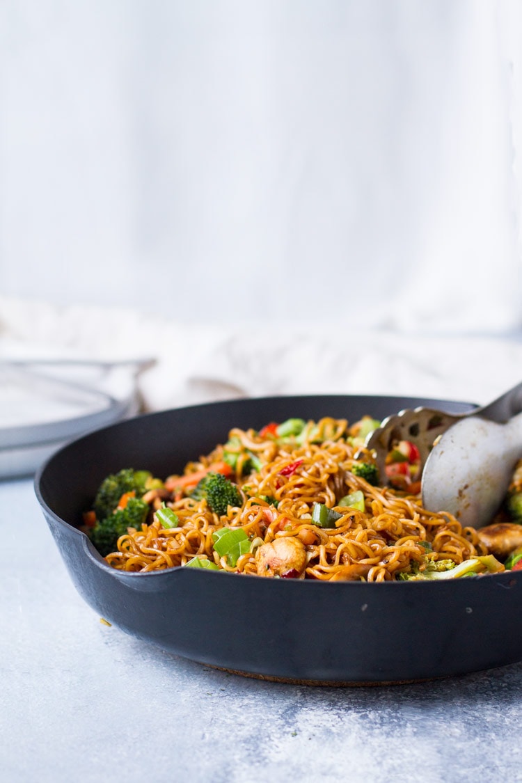Straight angle of lo mein in a skillet, white background and blue table