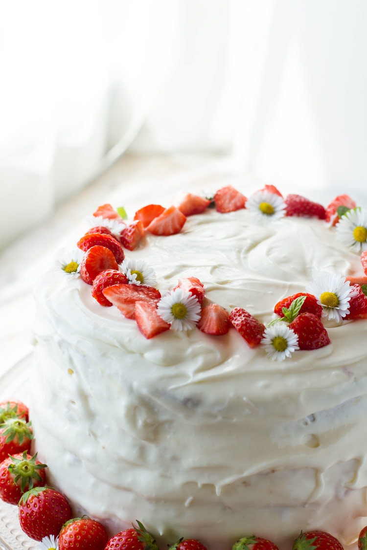 Strawberry cake with cream cheese frosting and strawberries as garnish.