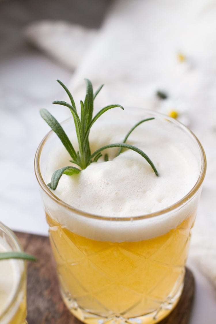 Apricot rosemary gin fizz with egg white foam and rosemary garnish.