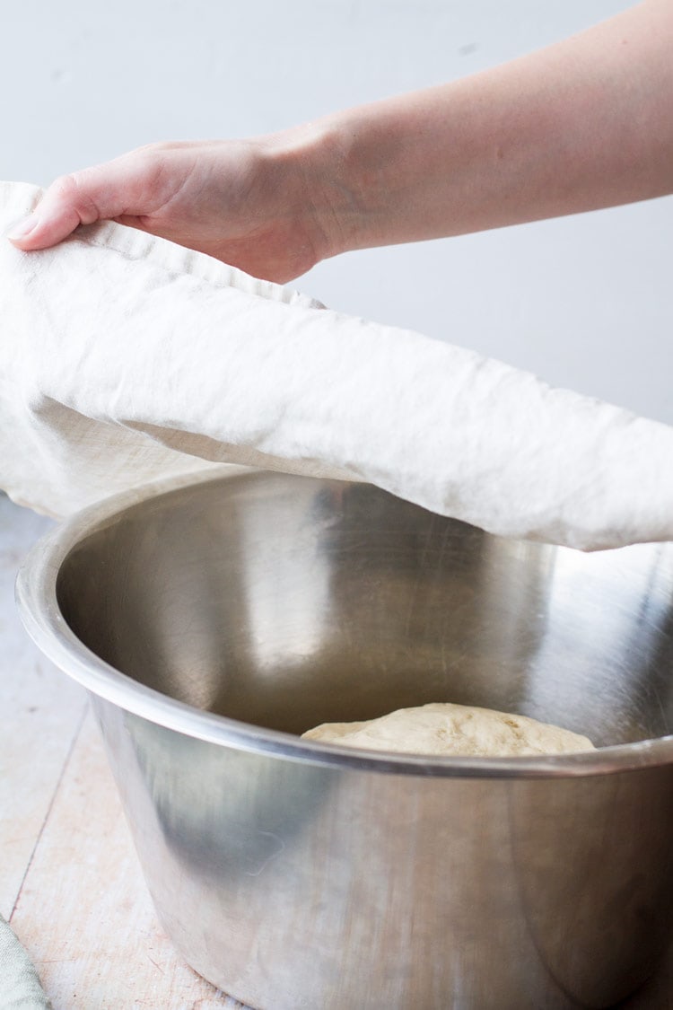 Covering dinner rolls dough with towel.