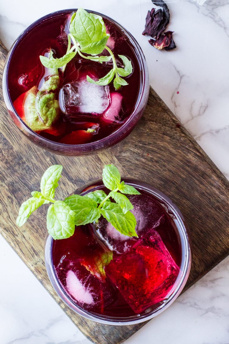 Two glasses with hibiscus tea and mint sprigs. Flatlay.