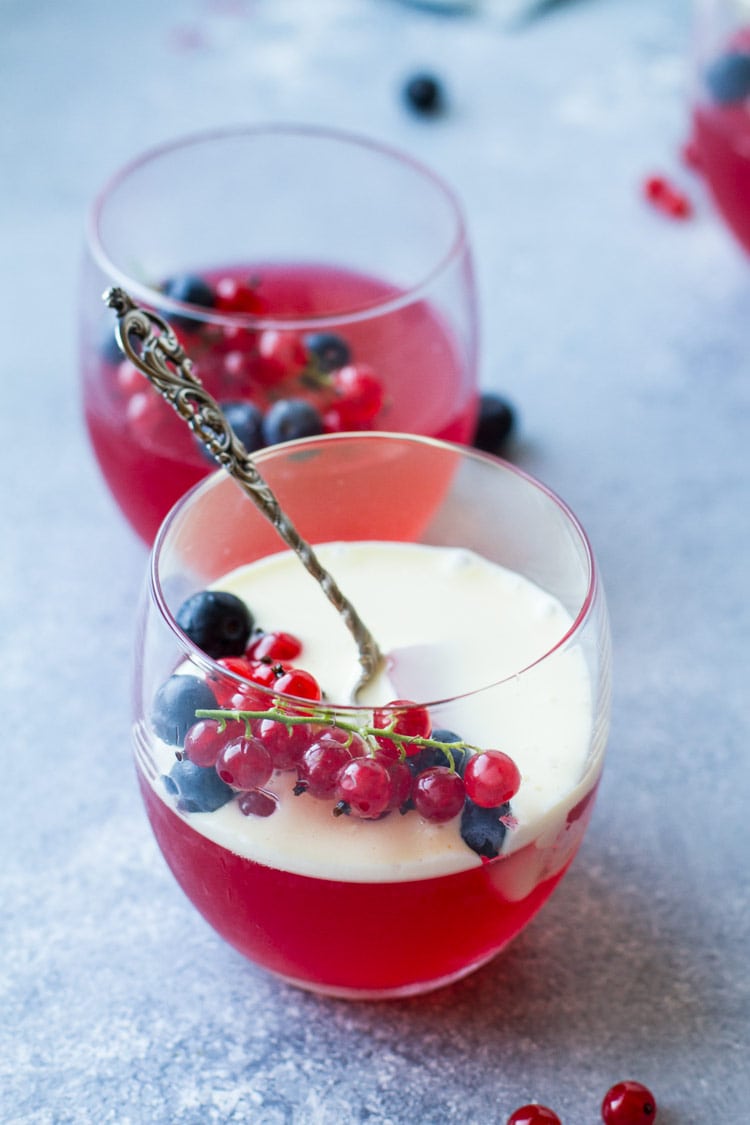Two glasses with jello recipe, berries and one with custard sauce.