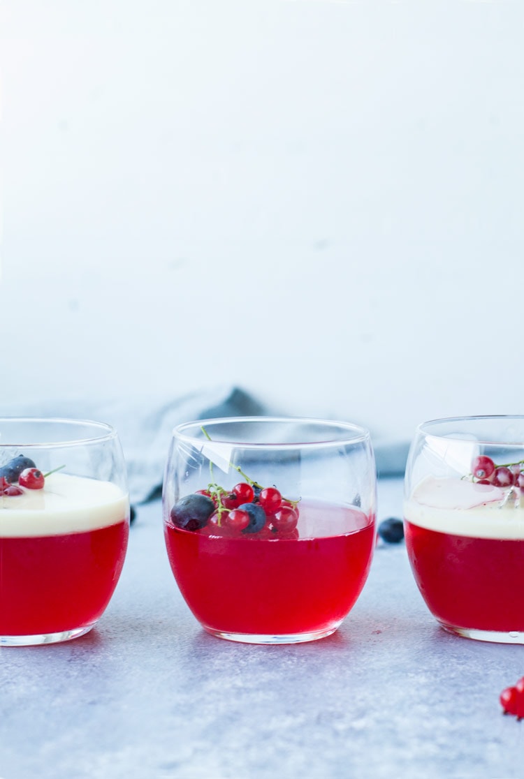 Three glasses with homemade jello, berries and two with vanilla custard. Straight on.