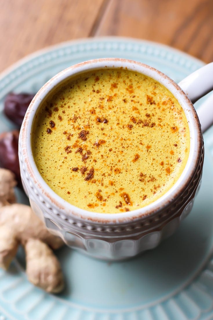 Yellow hot drink with turmeric and dates, garnished with powdered spices.