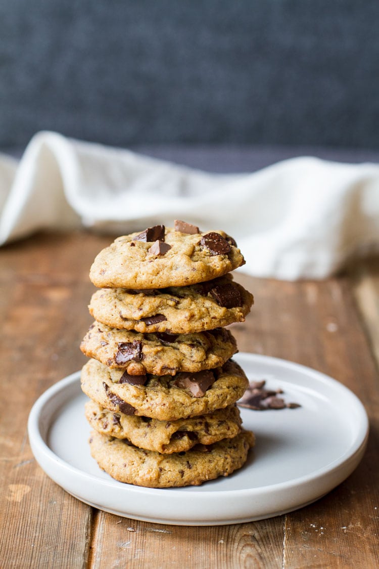Stack of peanut butter chocolate chip cookies on a white plate. Wooden background. Pinterest pin.