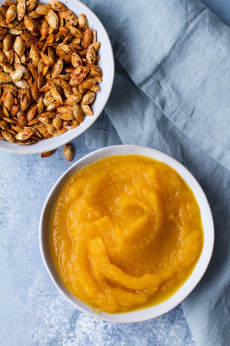 Pumpkin puree in a blue bowl on a blue table, flatlay.