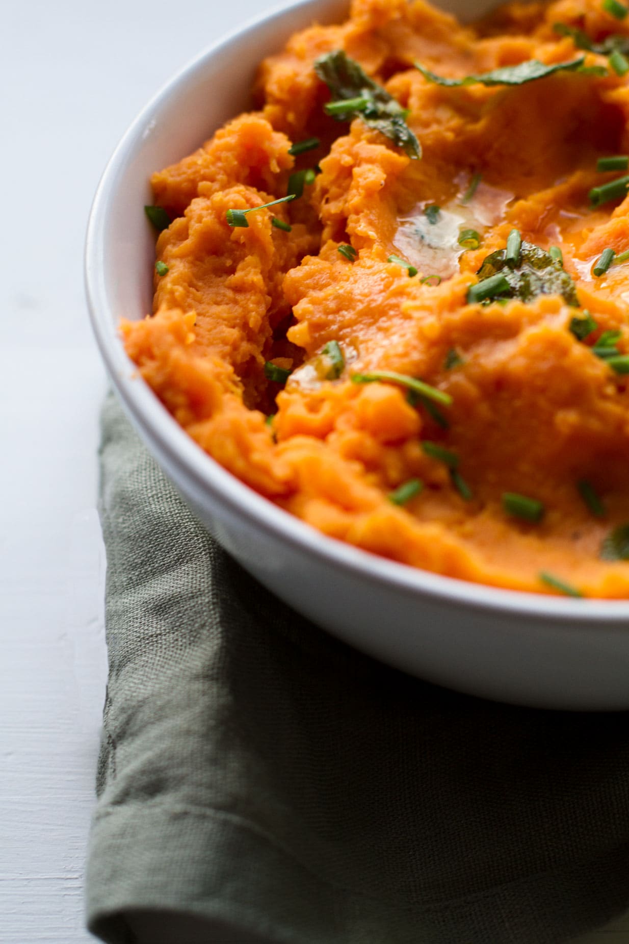 A white bowl with cheddar herb sweet potato mash, close up.