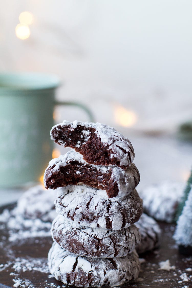 Fudgy chocolate crinkle cookies stacked, the top two are open. Turquoise mug in the background.