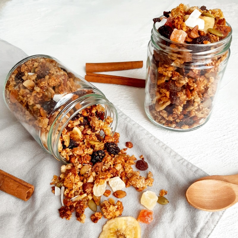 Glass jar tipped over with heathy granola spilling out.