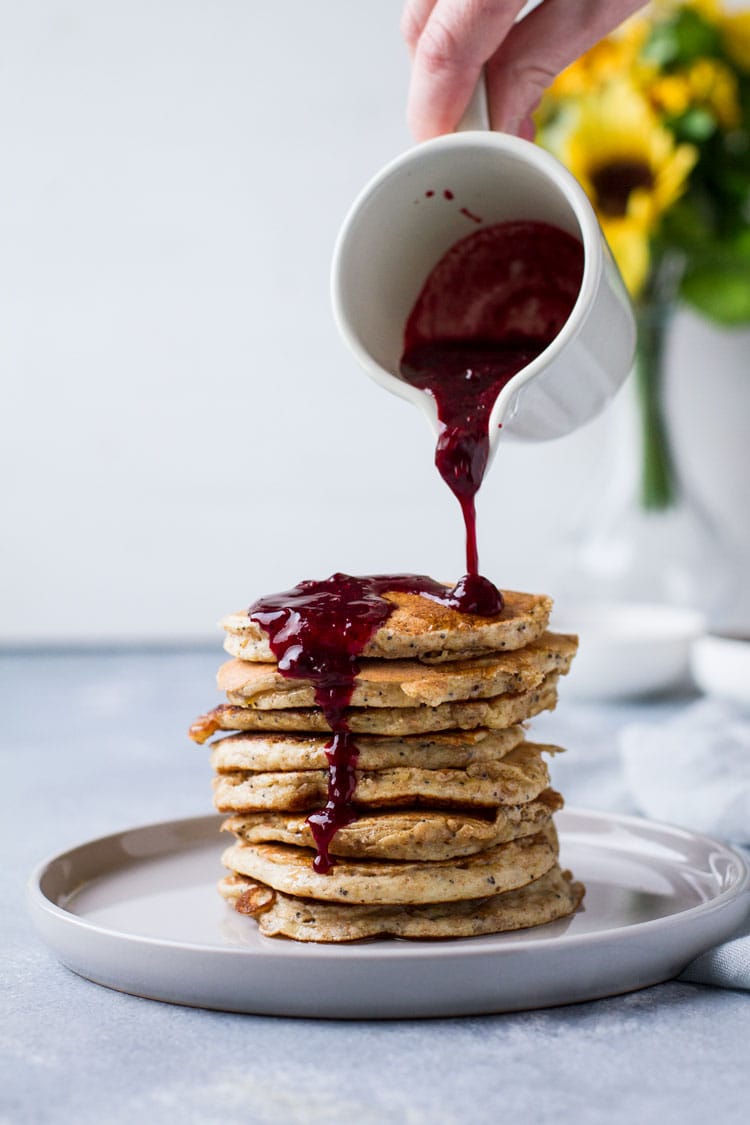 Pouring blackberry syrup on lemon poppy seed pancakes.