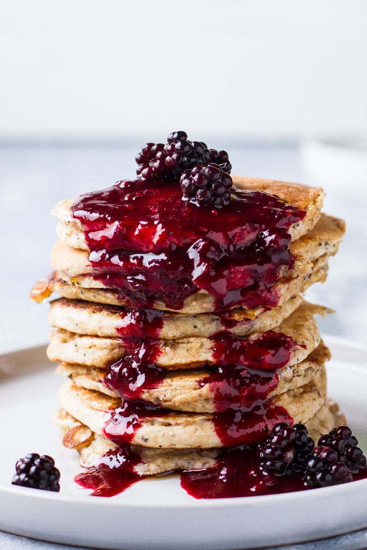 Lemon Poppy Seed Pancakes with blackberry syrup down their sides.