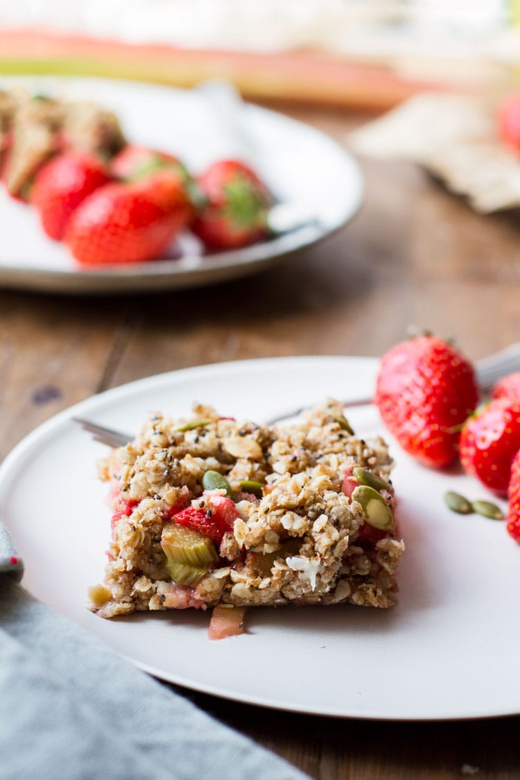 Square oatmeal bar and strawberries on a white plate.