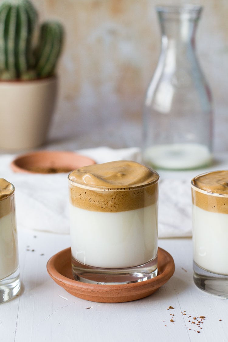 Three glasses with milk and topped with foamy whipped coffee.
