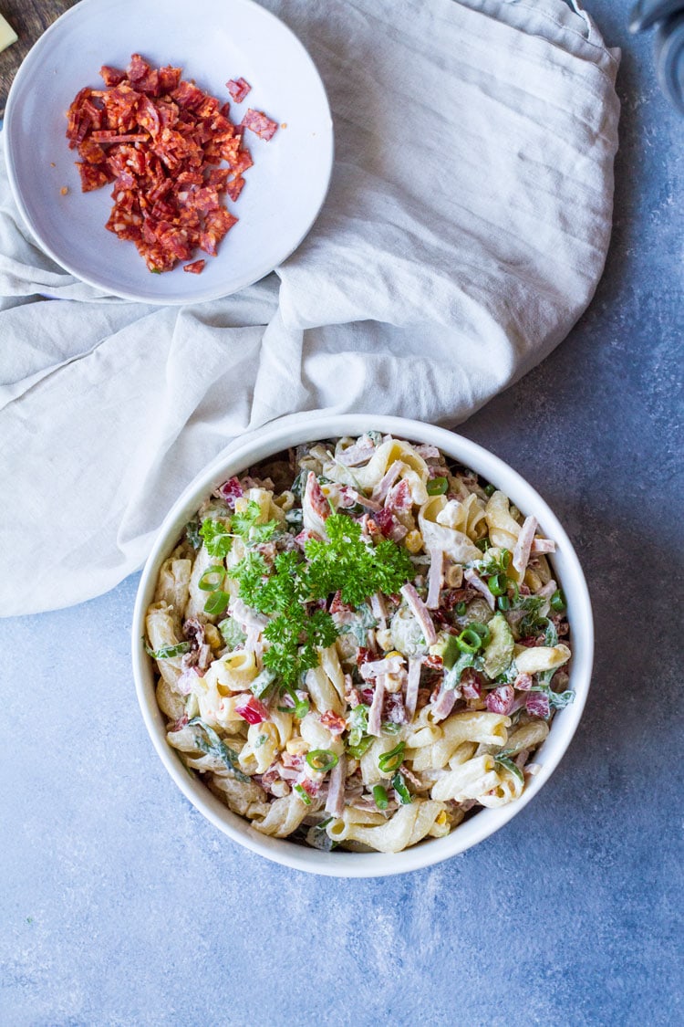 Creamy pasta salad in a white serving bowl, flatlay.
