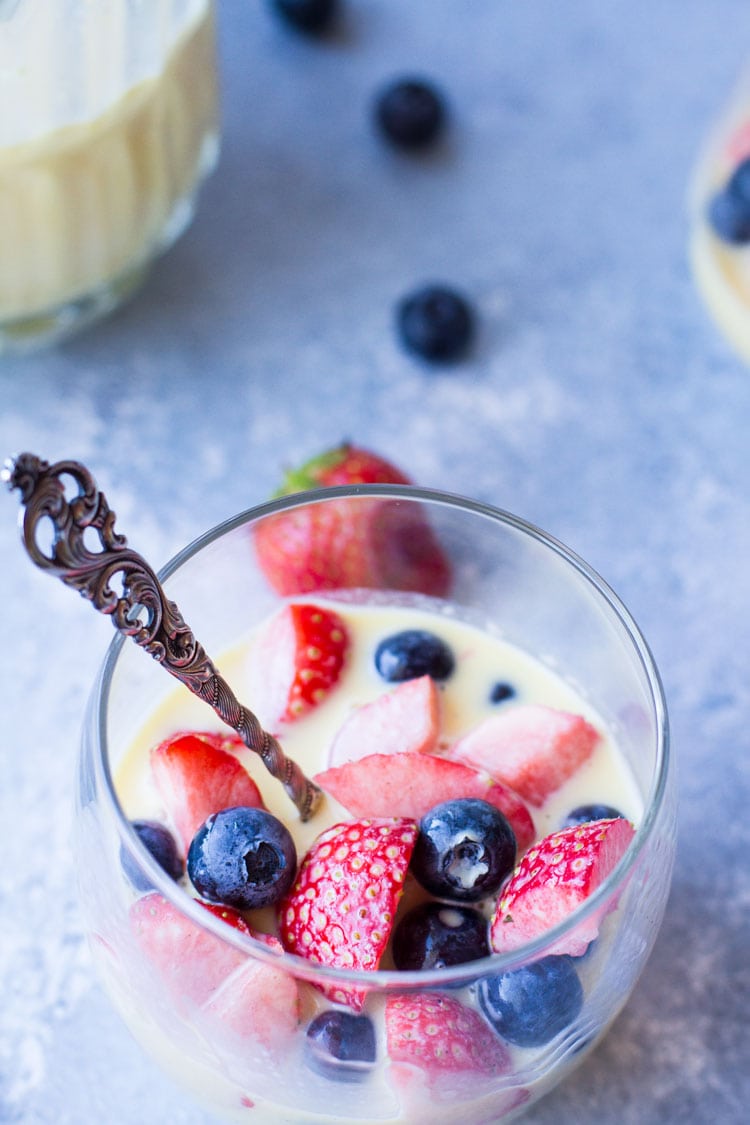 Vanilla custard sauce, strawberries and blueberries in a glass.