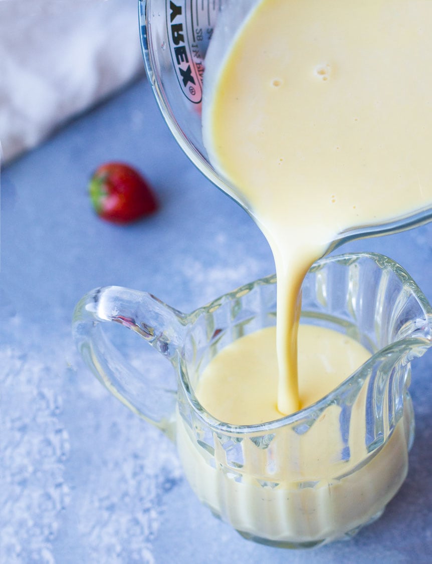 Pouring crème anglaise into a glass pitcher.