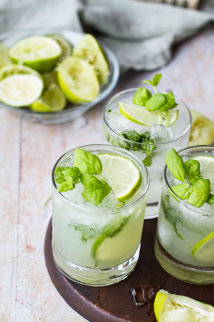 Three glasses filled with mint, lime and mojito.