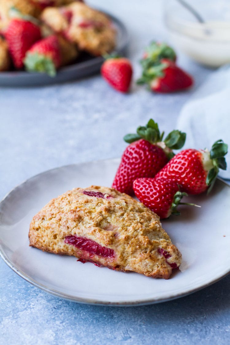 Strawberry scones on a plate with some fresh strawberries on the side.