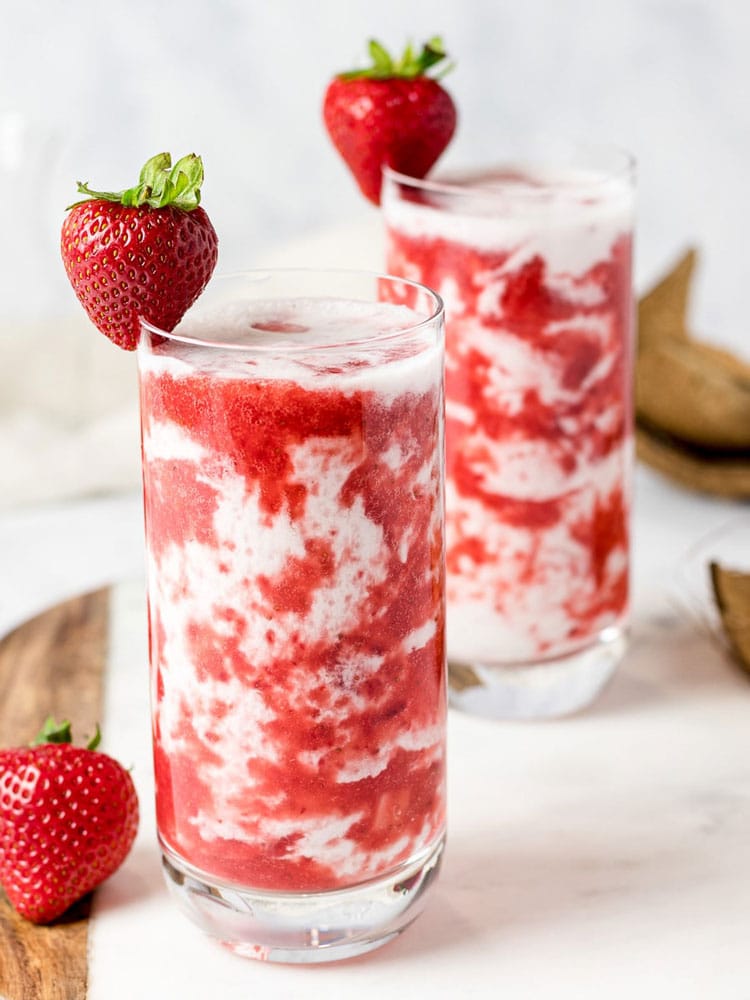 Tall glass with milk and strawberry puree.