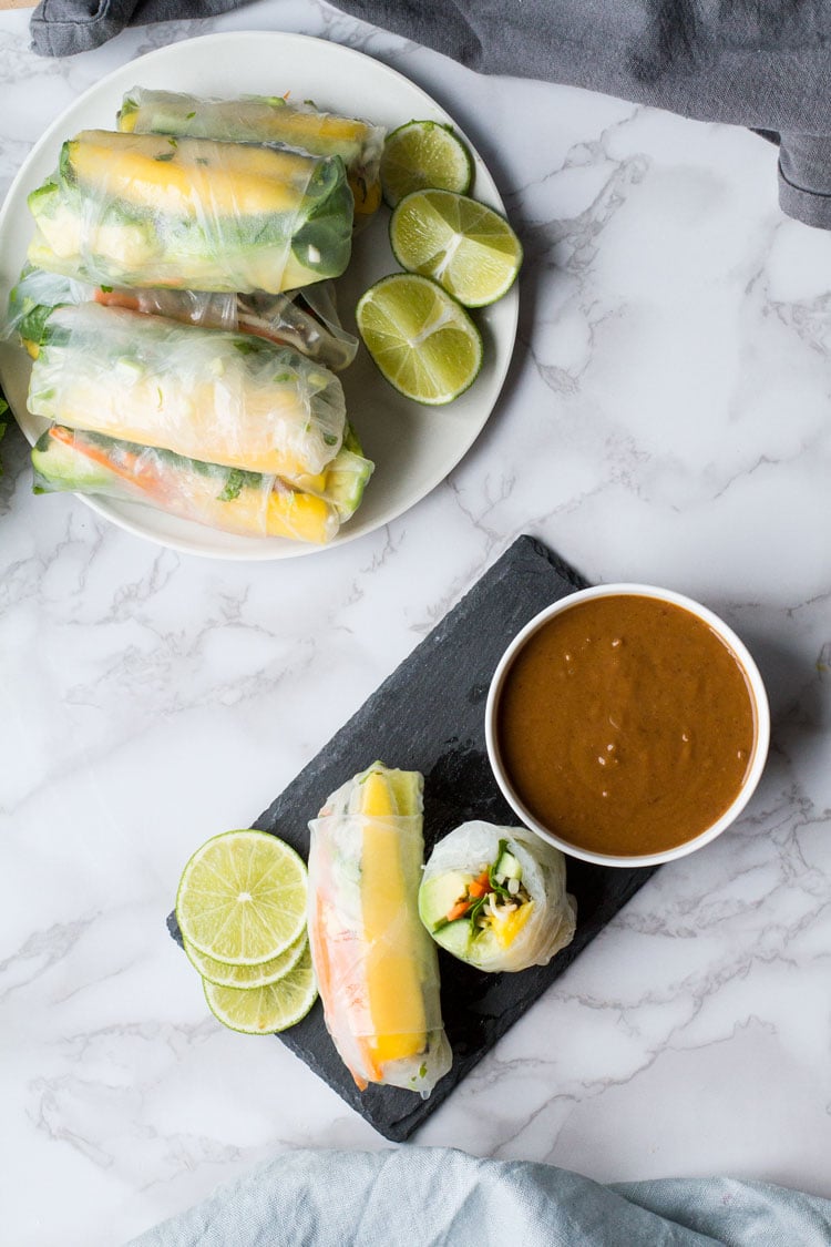 Plate with summer rolls and a slate with peanut sauce and more cut open summer rolls.