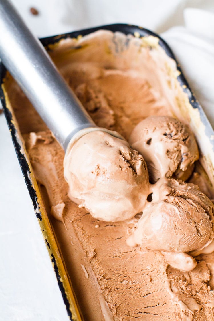 Chocolate ice cream in a bread pan, three scoops with an ice cream scoop.