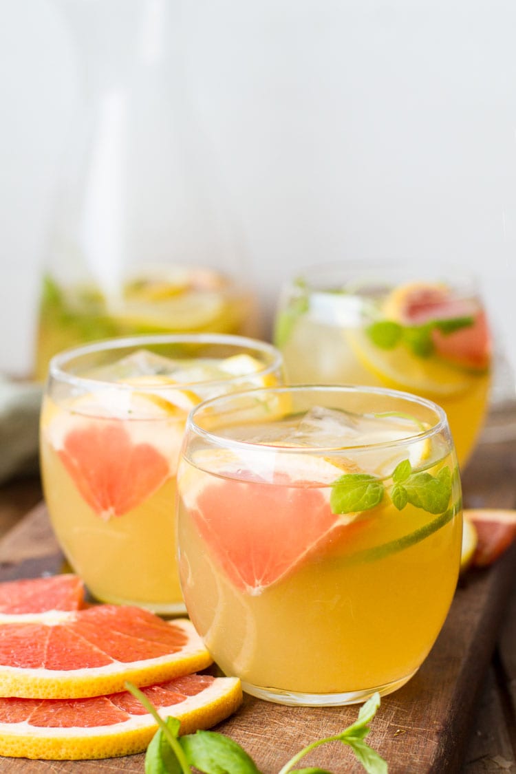 Three glasses with cold tea, ice cubes and sliced grapefruit.