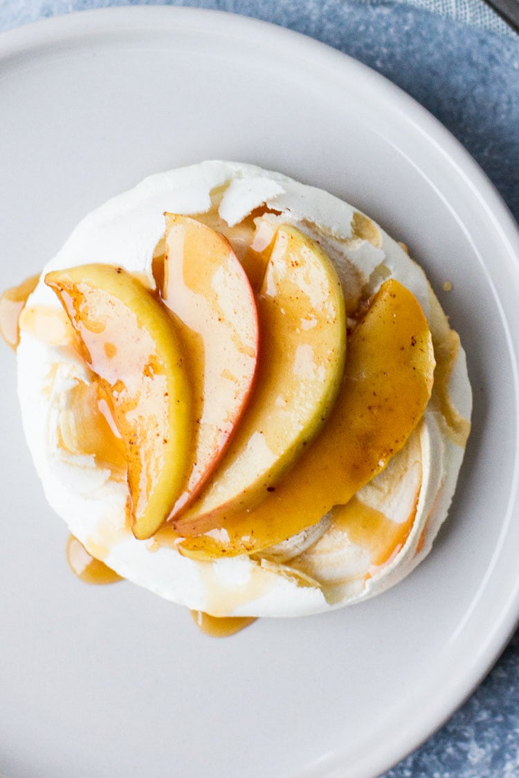 Close-up of one mini pavlova with sliced apples and caramel.