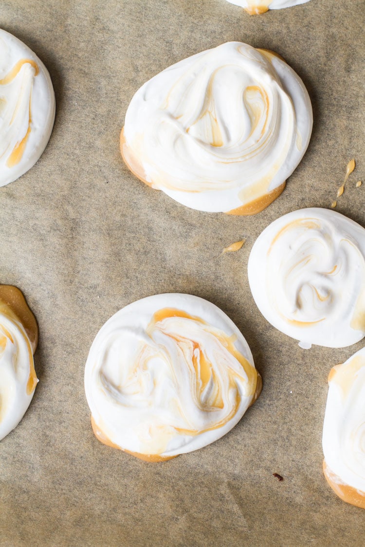 Caramel swirled mini pavlovas on baking tray, flatlay.
