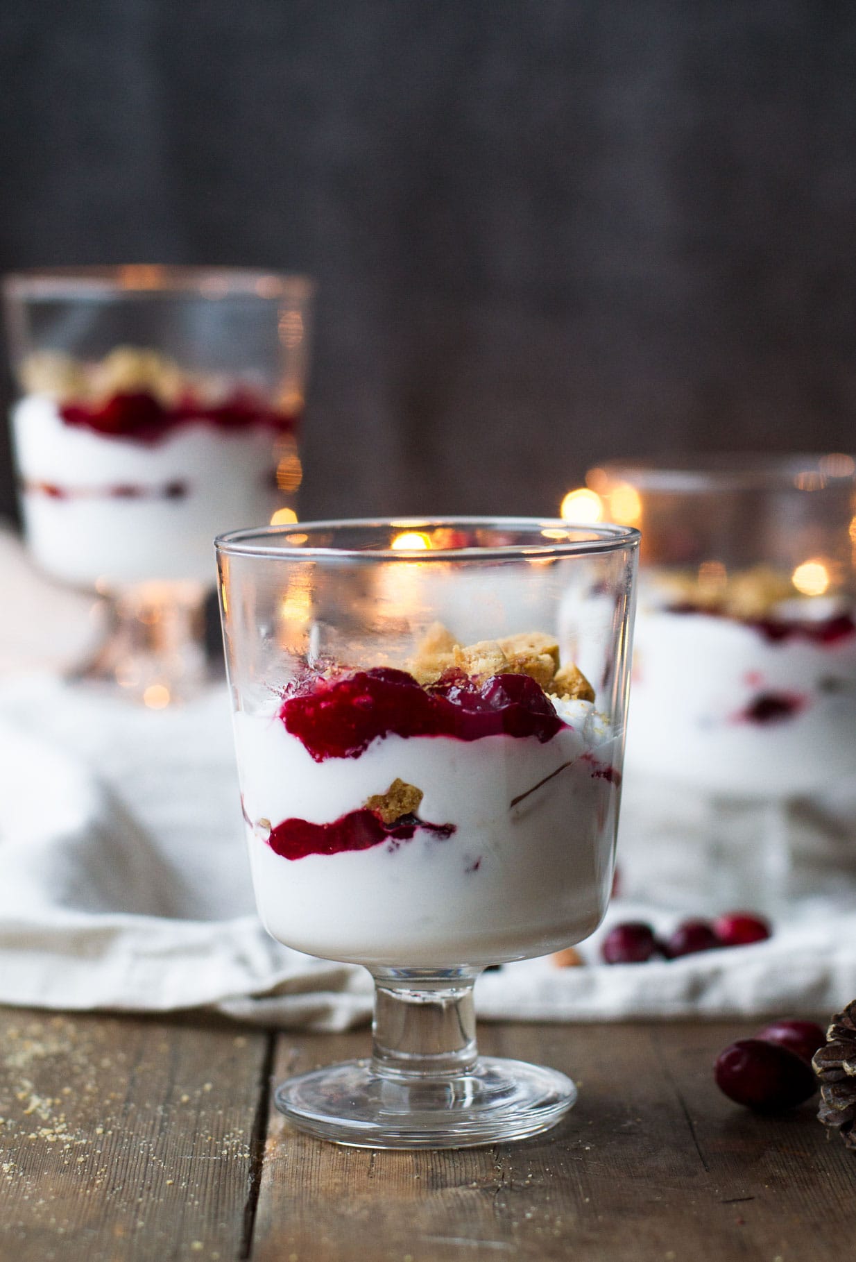 One glass with whipped coconut cream and cranberry sauce in the foreground and two blurred ones in the background.